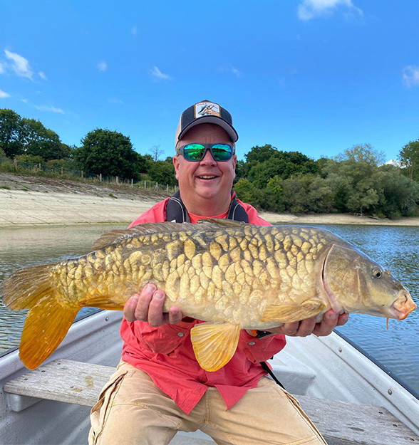 Angler in a Fishing Boat Holding a Carp Fish