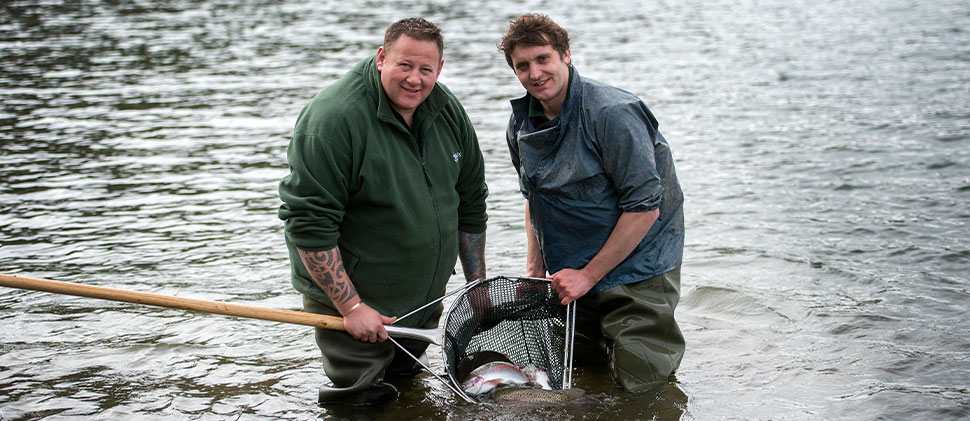 Two men with a net stood in the water at Clatworthy